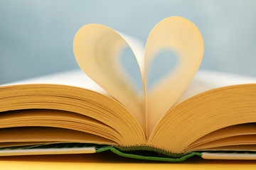 Heart made of pages. Book on yellow background, close up