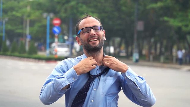 Happy young businessman unbutton shirt in the city, super slow motion