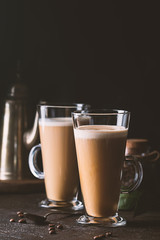Two glasses with cold coffee latte macchiato on table against black background