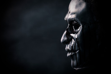 Fototapeta na wymiar Scary figure with creepy bloody mask in the dark
