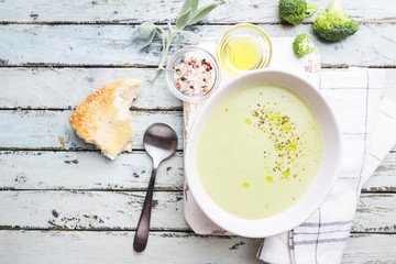 Broccoli cream soup in white bowl on wooden background, top view