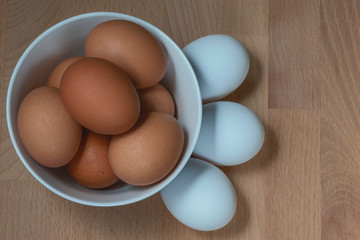 several fresh chicken eggs in a ceramic cup on a wooden background. Healthy eating concept