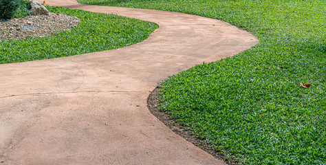 Brown concrete pathway cross green grass in the park