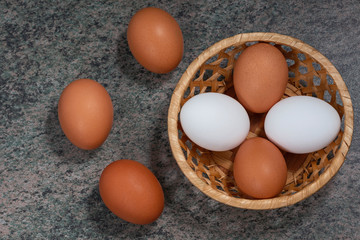 several fresh chicken eggs in a straw basket on a wooden background. Healthy eating concept.