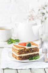 Slice of carrot cake with cream cheese frosting on wooden table