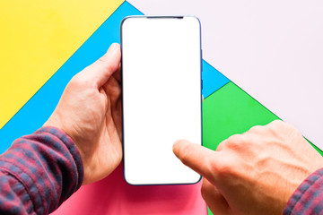 holding a smartphone with a blank white screen and clicks on the touch screen of the phone on a colored background