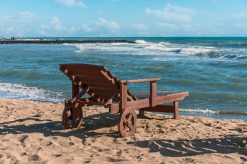 Fototapeta na wymiar one deck chair on the sandy beach of the Italian resort town of Lido di Ostia against the blue sea
