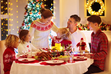 Family with kids having Christmas dinner at tree