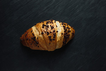 Fresh and tasty croissant with chocolate on wooden background