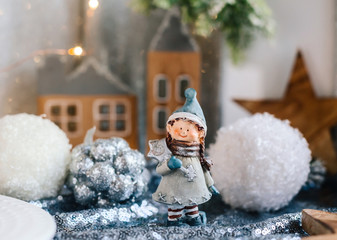 Porcelain figurines of children in a Christmas decor. Winter figurines of a boy and a girl with gifts on the background of houses and cones. Christmas Greeting Card. Copy space.