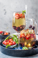 White wine sangria or punch with berries and ice in glass and pincher. Homemade refreshing fruit sangria.