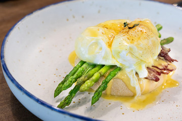 Serving of egg benedict with asparagus and bacon