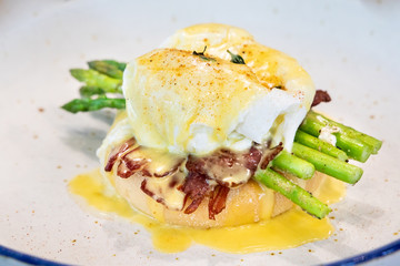 Serving of egg benedict with asparagus and bacon