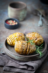 Baked hasselback potatoes with cheese, garlic and greens