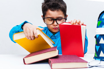 cute boy in glasses sitting at a Desk with books