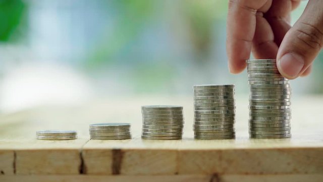 Businessman insert coins into stack coin. Saving money and business finance growth concept