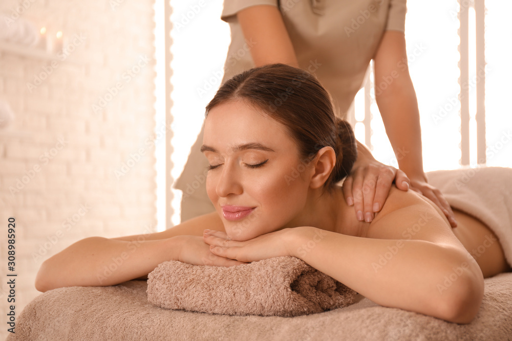 Poster Young woman having body scrubbing procedure with sea salt in spa salon