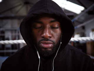 Male Boxer With Eyes Closed Training In Gym Listening To Music On Headphones In Boxing Ring