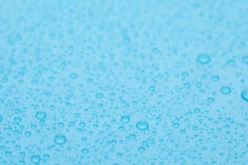 Water drops on light blue background, closeup view