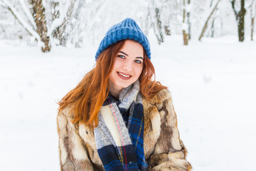 portrait of a cheerful young woman in the winter forest. beautiful girl in blue knitted hat in snowy forest