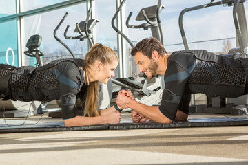 Man and woman doing electro muscular stimulation training in a modern gym - obrazy, fototapety, plakaty