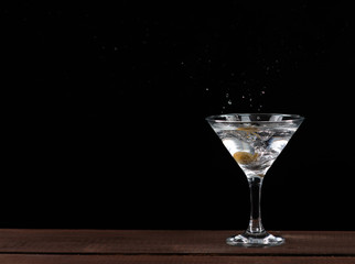 in a Martini glass falls olive, splashes of beautifully flying on black background