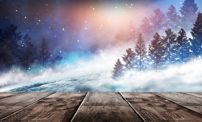 Winter background. Winter snow landscape with wooden table in front. Dark winter forest background at night. Snow, fog, moonlight. Dark neon night background in the forest with moonlight. 