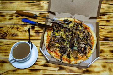 fresh pizza with mushrooms and a cup with coffee, top view, selective focus