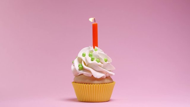 Delicious birthday cupcake with candle on pink background