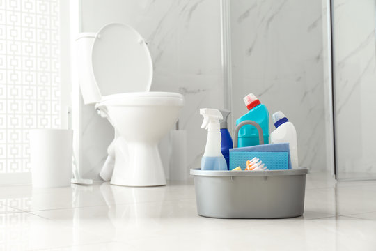 Cleaning supplies near toilet bowl in modern bathroom. Space for text