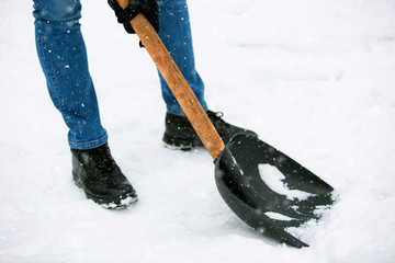 Man with shovel cleaning snow at day light in his backyard