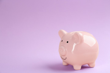 Piggy bank on violet background. Space for text