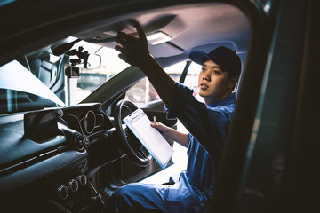 Mechanic holding clipboard and checking inside car to maintenance vehicle by customer claim order...