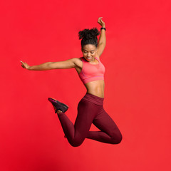 Happy athletic girl in sportwear jumping up