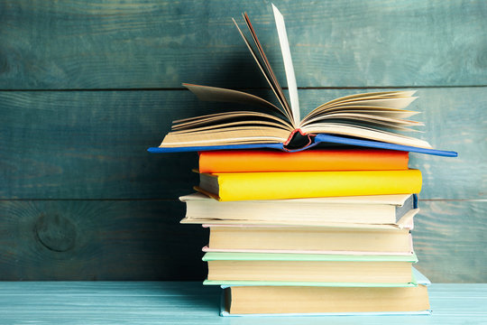 Stack of colorful books on light blue wooden table