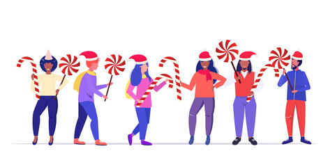 mix race people in santa claus hats holding sweetmeats candy cane and lollipop merry christmas happy new year winter holidays celebration concept horizontal full length vector illustration
