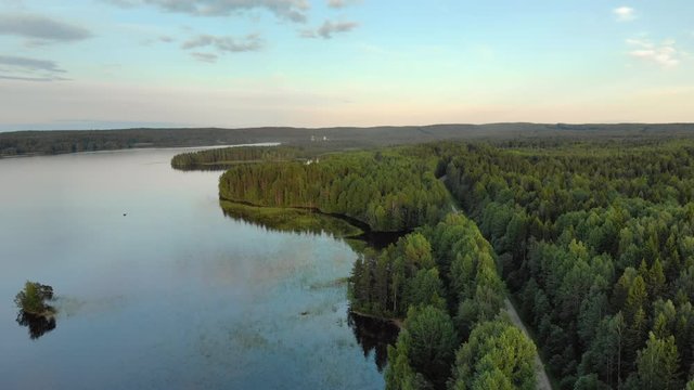 The magnificent landscape of the Northern nature. Coastal zone of lake Onega near dense coniferous forest with a country road in Karelia. Aerial view