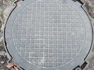 old cast iron manhole cover on bare ground