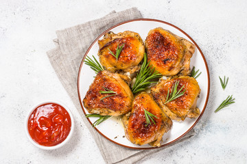 Baked chicken thighs with herbs on white plate.