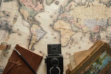 top view of vintage camera, notepad with fountain pen and painting on map background