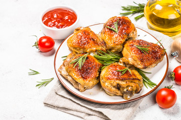 Baked chicken thighs with herbs on white plate.