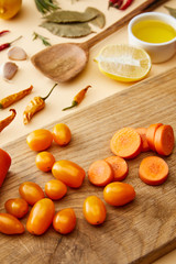 Selective focus of fresh vegetables on cutting board with spices and olive oil on beige background