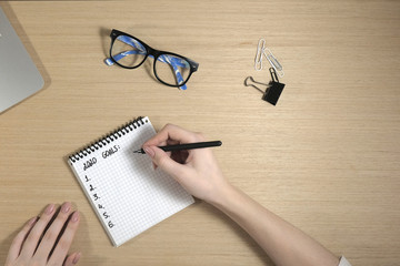 2020 goals. A workplace with a laptop. The girl is writing. View from above. Copy space. Flat lay