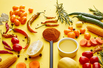 Ripe vegetables with olive oil and spices on yellow background