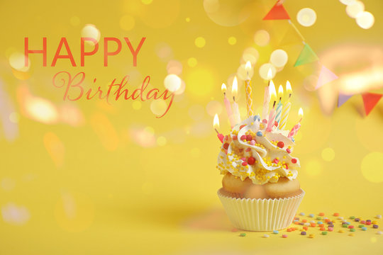 Delicious cupcake with candles on yellow background. Happy Birthday