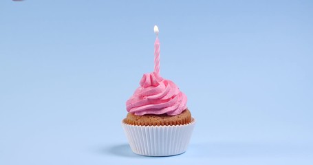 Woman lighting birthday candle on blue background, closeup