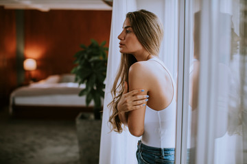 Young woman standing by the window in the room