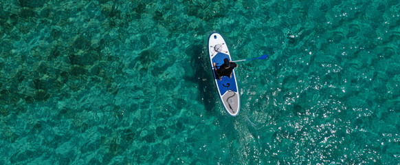 Aerial drone ultra wide photo of fit unidentified man practising in SUP board or Stand UP Paddle...