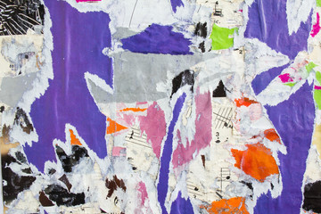 Colorful torn and peeling old crumpled pieces of paper posters and placards layers on dirty...