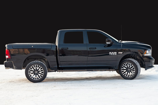 Black Dodge Ram with an engine of 5.7 liters side view on the background of black wall